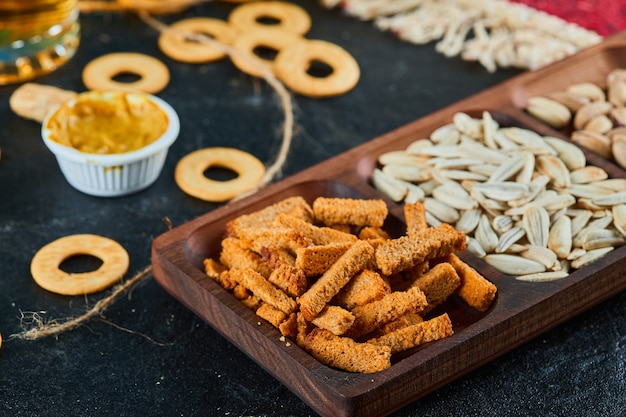 Plate of assorted snacks and crackers on dark table.