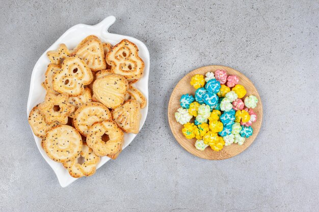 A plate of biscuit chips and a handful of popcorn candy on marble background. High quality photo