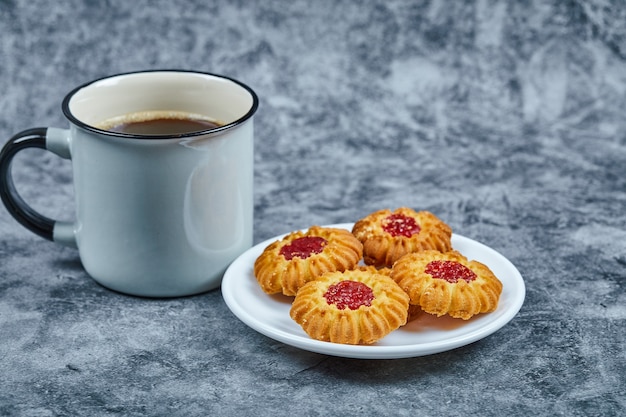 A plate of biscuits and coffee on marble table.