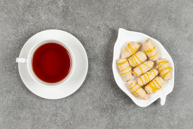 Plate of biscuits and cup of tea on marble surface