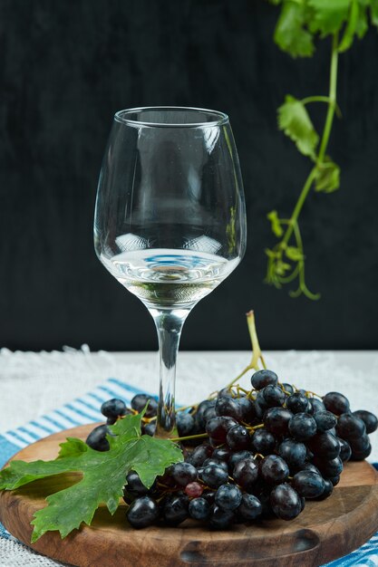 잎과 어두운 배경에 와인 한 잔과 검은 포도 접시. 고품질 사진