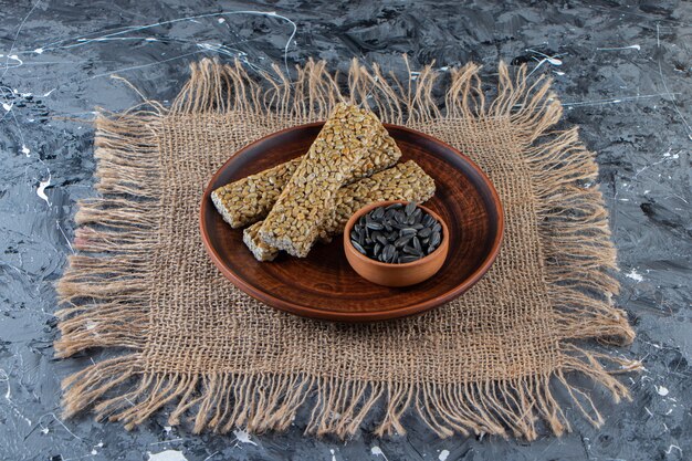 Plate of brittle candies with sunflower seeds on marble surface.