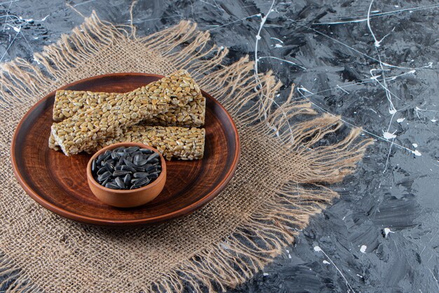 Plate of brittle candies with sunflower seeds on marble surface. 