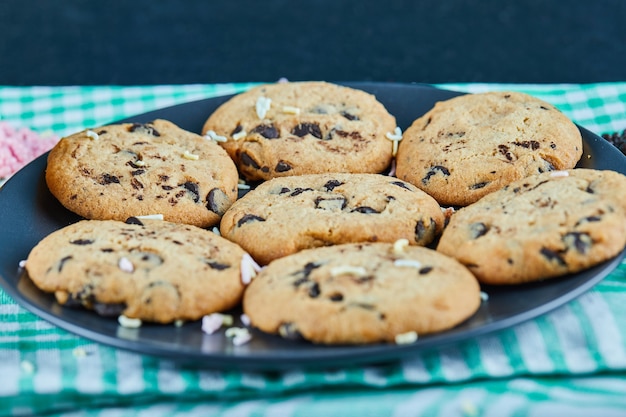 A plate of chocolate chips cookies on dark table