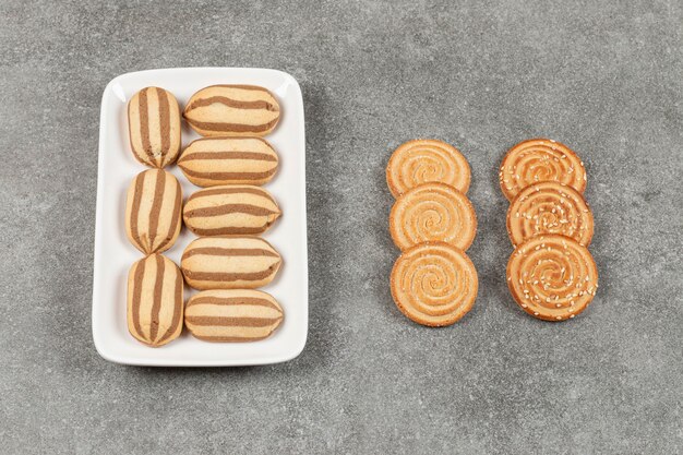 Plate of chocolate striped biscuits and crackers on marble surface