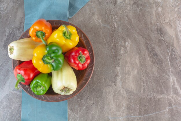 Plate of colorful fresh bell peppers on marble surface