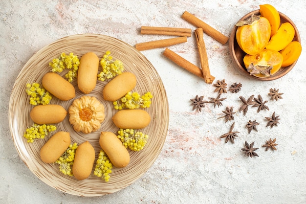 Un piatto di biscotti e bastoncini di cannella e anice stellato e una ciotola di palma su fondo di marmo