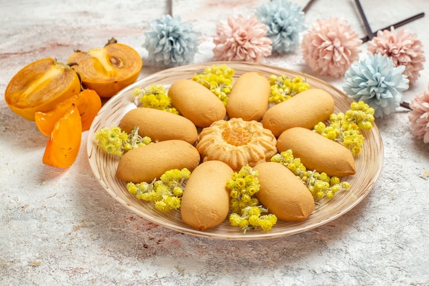 Foto gratuita un piatto di biscotti e palme e fiori blu e rosa pallidi su fondo bianco