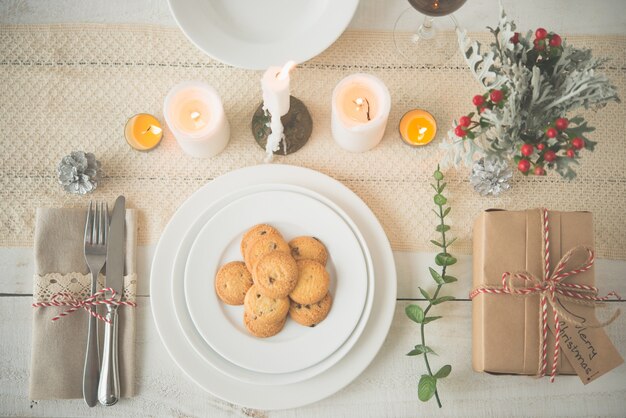 Plate of cookies and present on dinner table with Christmas decorations