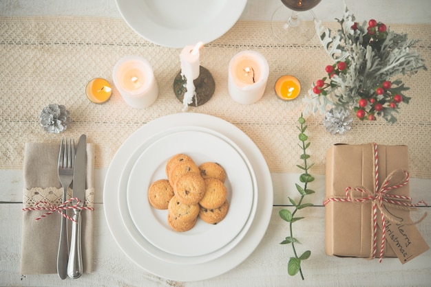 Plate of cookies and present on dinner table with Christmas decorations