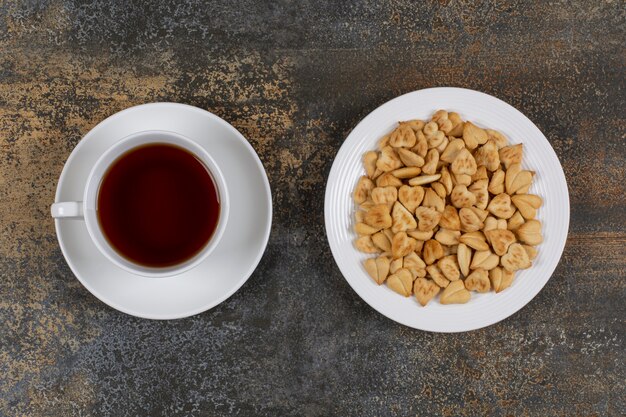 Plate of crackers and cup of tea on marble.