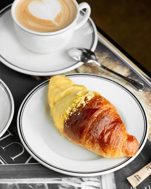 Plate of croissant half dipped into vanilla cream