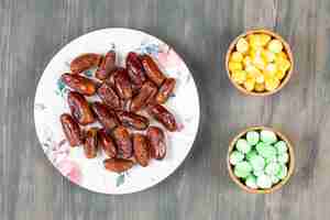 Free photo plate of dates and colorful candies on wooden surface