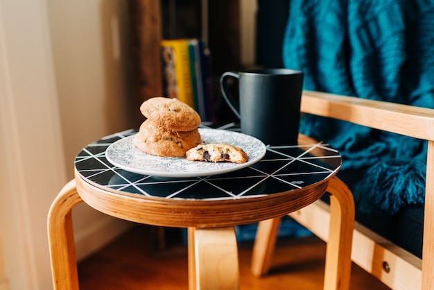 Free photo plate of delicious cookies next to a black mug of coffee on black table in a coffee house