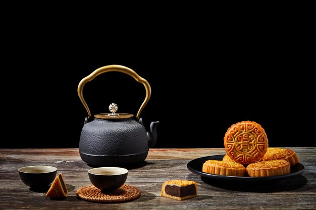 Тарелка вкусного печенья и чайник на деревянной поверхности