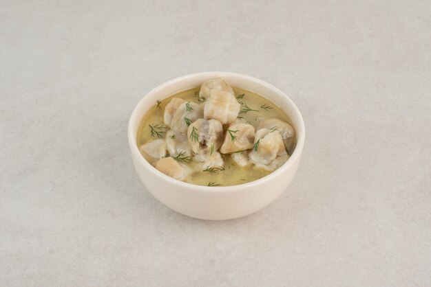 Plate of dumplings with greens on white background .