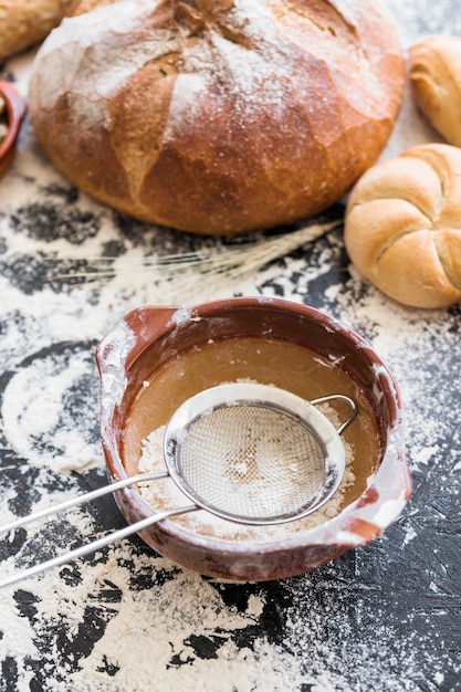 Piatto di farina e setaccio con panetteria sul tavolo