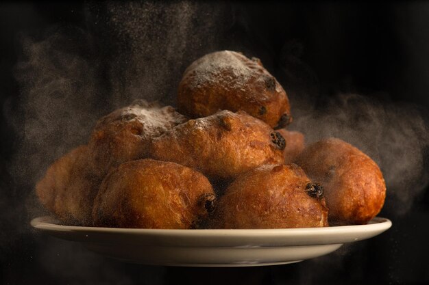 Free photo plate of fresh oliebollens just out of the oven with baking powder over them