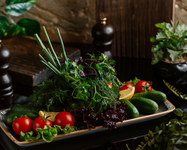 Тарелка свежих сезонных овощей, включая помидоры, огурцы и зелень