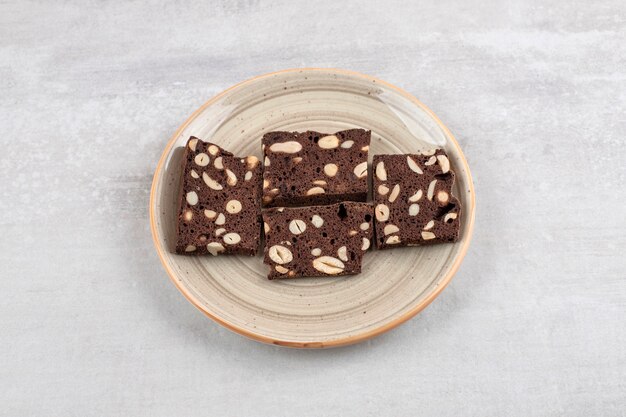 A plate full of brown bread slices with nuts on a stone table. 