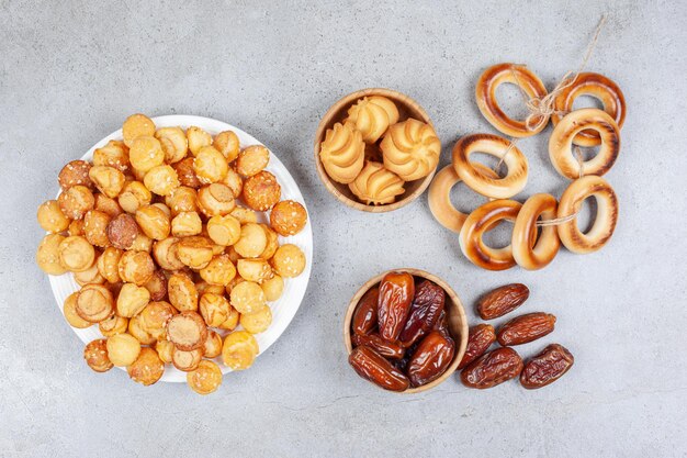 Plate full of cookies next to bowls of dates, cookies and tied sushki. High quality photo