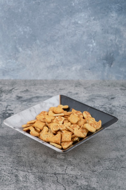 Free photo plate full of dry salted crackers on marble background.