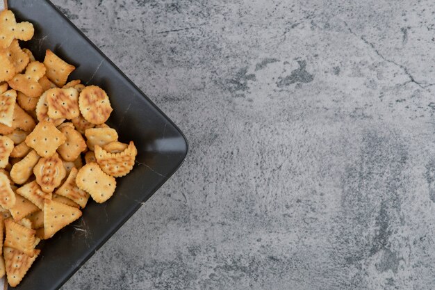 Plate full of dry salted crackers on marble.