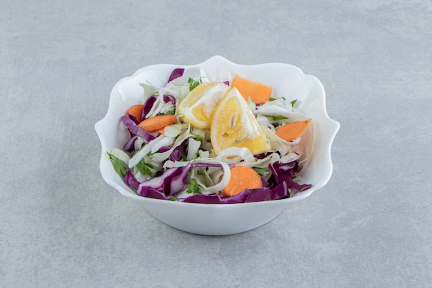 A plate of grated vegetables with lemon , on the marble background.
