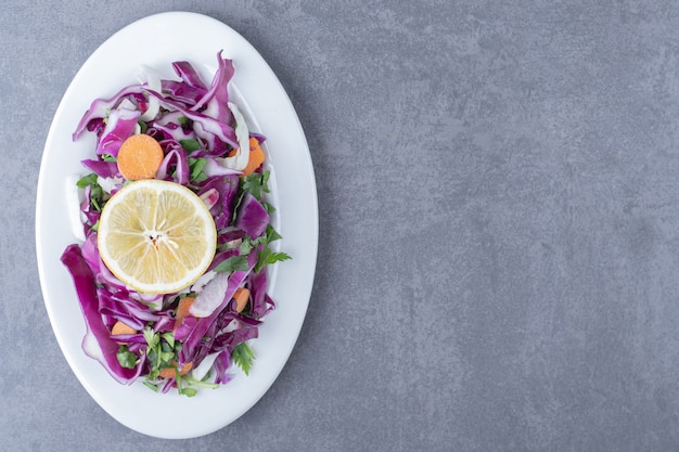 Free photo a plate of grated vegetables with lemon , on the marble surface.