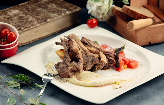 a plate of grilled lamb ribs with puree and fried potato