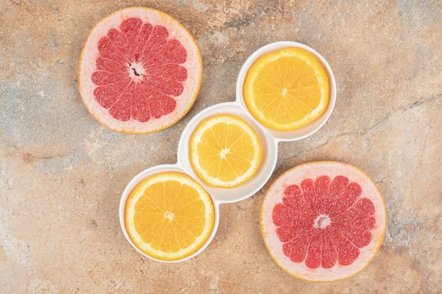 Free photo plate of lemon and grapefruit slices on marble surface.