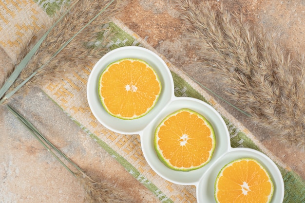 Тарелка ломтиков лимона на мраморной поверхности со скатертью.