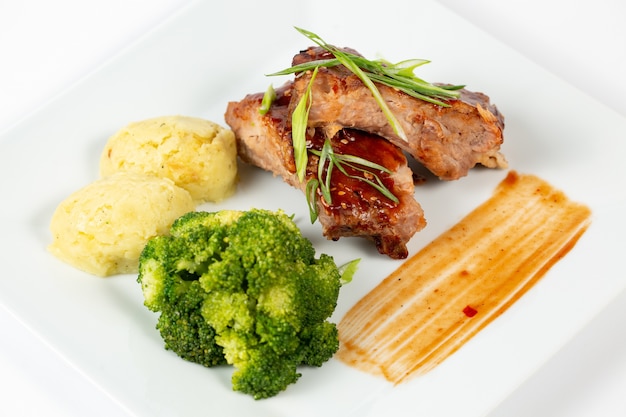 Plate of meat with barbecue sauce mashed potatoes and broccoli