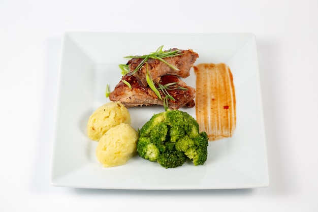 Plate of meat with barbecue sauce mashed potatoes and broccoli