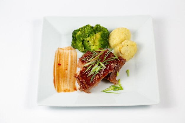 Plate of meat with barbecue sauce mashed potatoes and broccoli