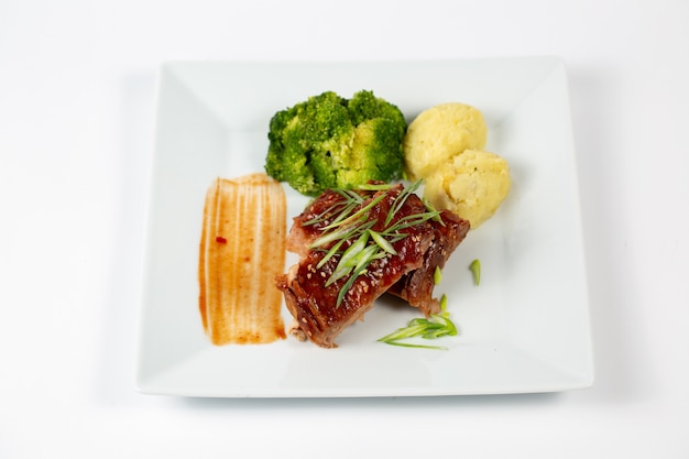 Plate of meat with barbecue sauce mashed potatoes and broccoli