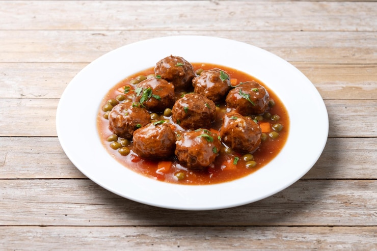 Free Photo a plate of meatballs with sauce and beans on a wooden table