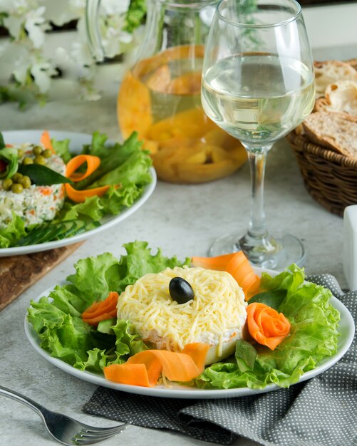 Тарелка с мимозой салас, украшенная кусочками моркови и листьями салата