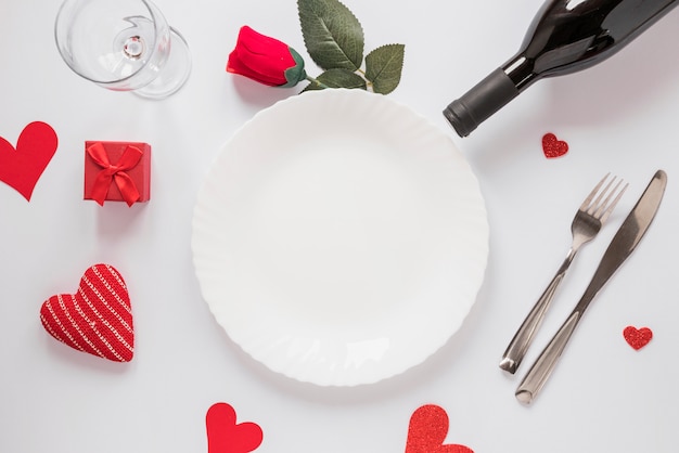 Plate near bottle, glass, flower and ornament hearts 