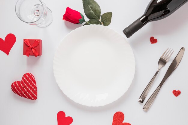 Plate near bottle, glass, flower and ornament hearts 