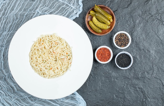 暗い表面に麺、漬物、スパイスのプレート。