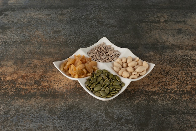 Plate of nuts, seeds on marble table .