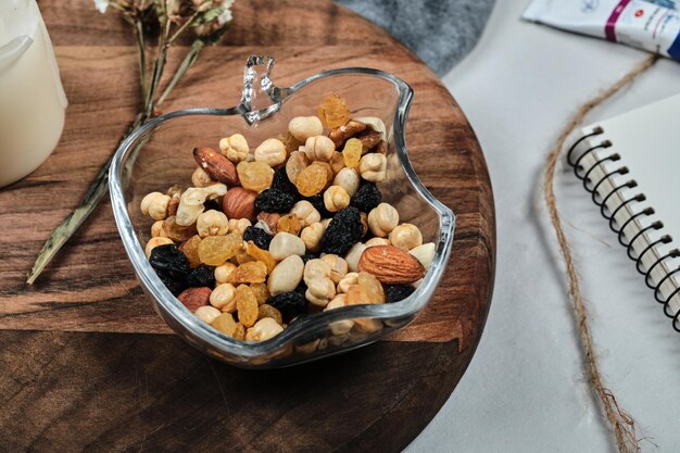 A plate of nuts with candle, flower, paper and tubes on wooden board.