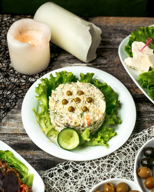 Тарелка оливкового салата с огурцом и листьями салата