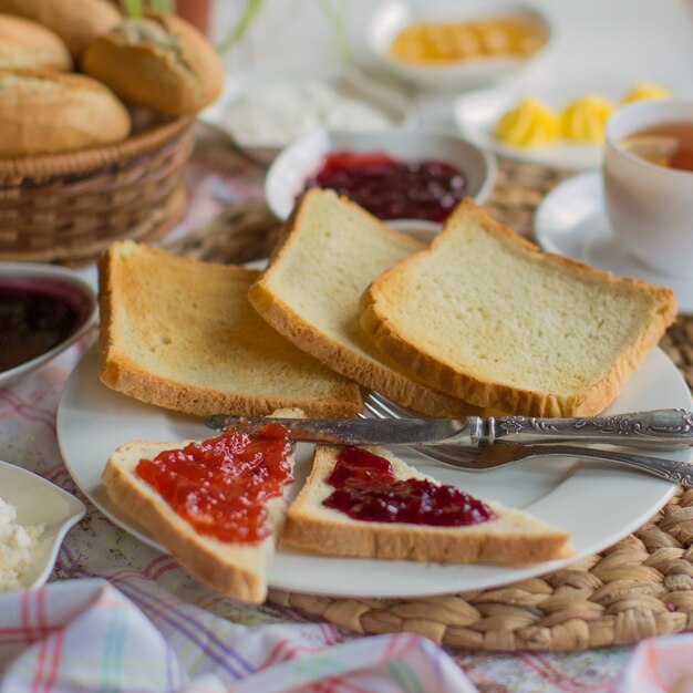 A plate of plain square toast slices and triangular toasts with jam