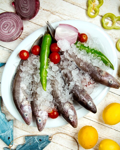 Plate of raw fish topped with pepper, cherry tomato and red onion