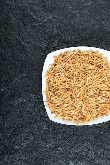 Plate of raw pasta on black.