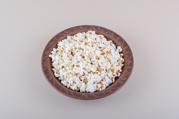 Plate of salted popcorn for movie night on white surface. High quality photo