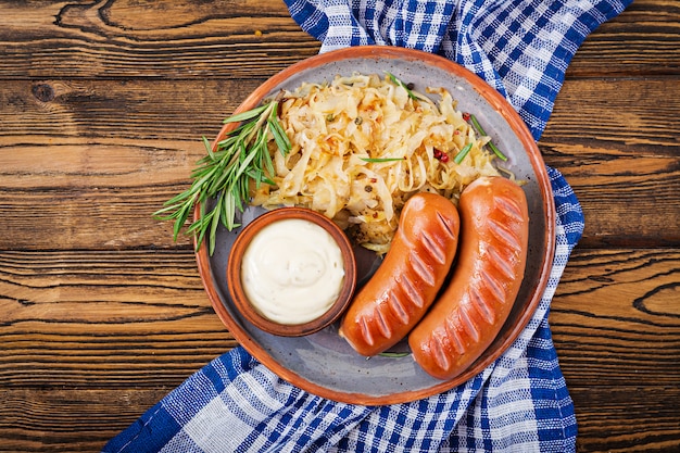 Plate of sausages and sauerkraut on wooden table. Traditional Oktoberfest menu. Flat lay. Top view.