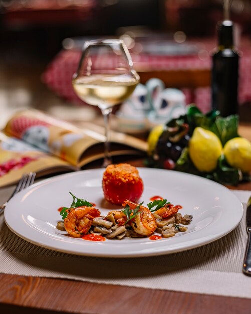 A plate of sauteed mushroom and shrimp served with tomato